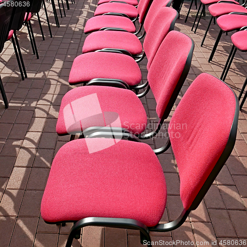 Image of Rows of office chairs with crimson color seats outdoors