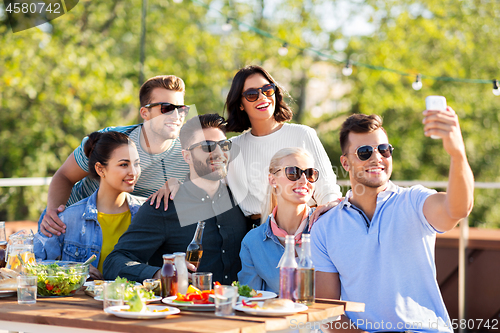 Image of happy friends taking selfie at rooftop party