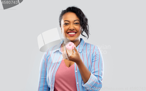 Image of happy african american woman eating pink donut