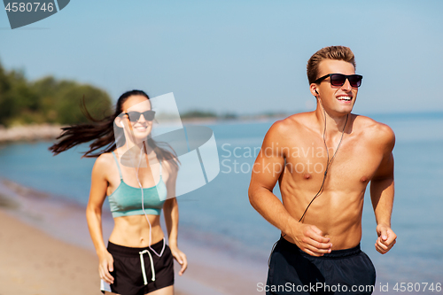 Image of couple with earphones running along on beach