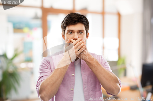 Image of shocked man closing mouth by hands at office room