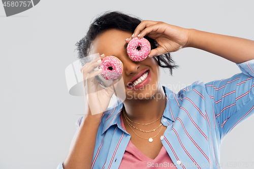 Image of happy african american woman with eyes of donuts