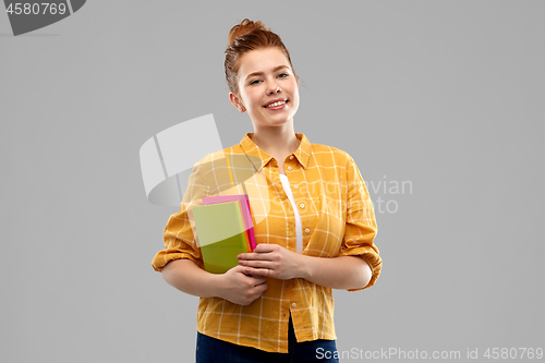 Image of smiling red haired teenage student girl with books