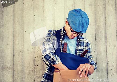 Image of hipster man looking for something in his bag