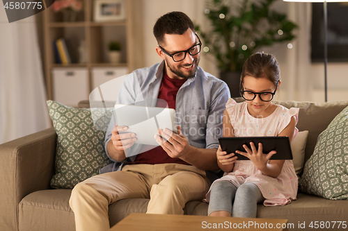 Image of father and daughter with tablet computers at home