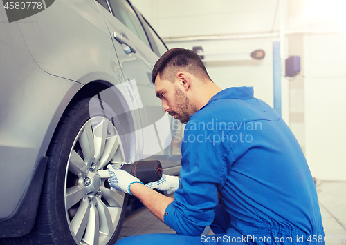 Image of mechanic with screwdriver changing car tire