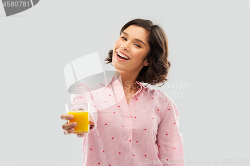 Image of happy young woman in pajama holding orange juice