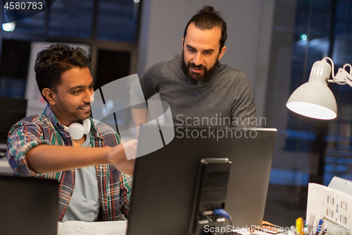 Image of creative team with computer working late at office