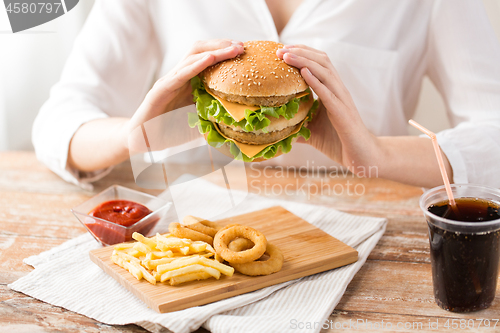 Image of close up of woman eating hamburger at restaurant