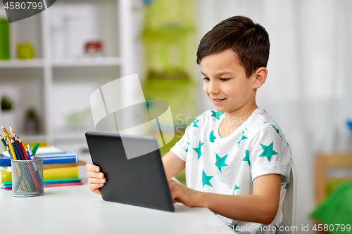 Image of student boy with tablet pc and notebook at home