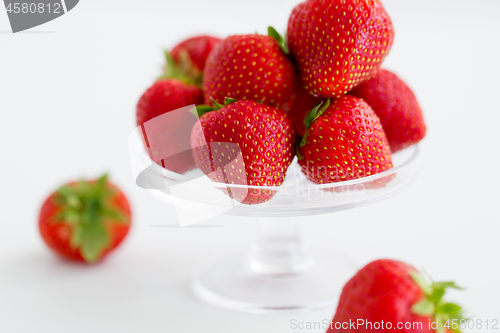 Image of strawberries on glass stand over white background