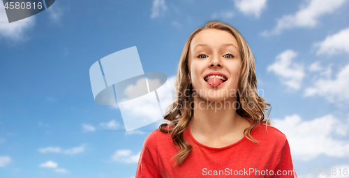 Image of teenage girl in red t-shirt shows tongue over sky