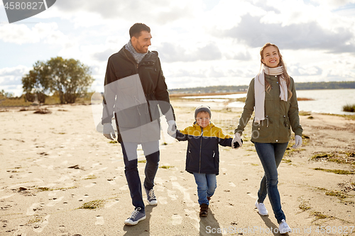 Image of happy family walking along autumn beach