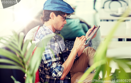 Image of man with tablet pc sitting at cafe table