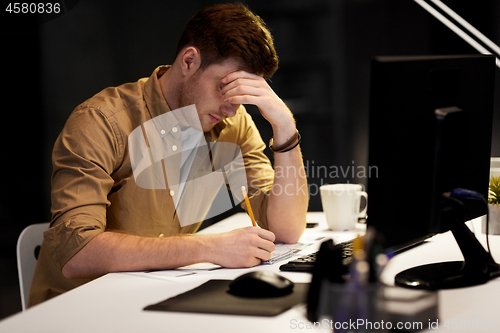 Image of man with notepad working late at night office