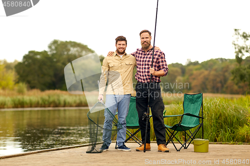 Image of friends with fishing rod and net at lake or river