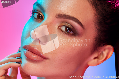 Image of High Fashion model woman in colorful bright lights posing in studio