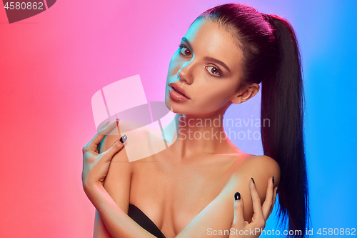 Image of High Fashion model woman in colorful bright lights posing in studio