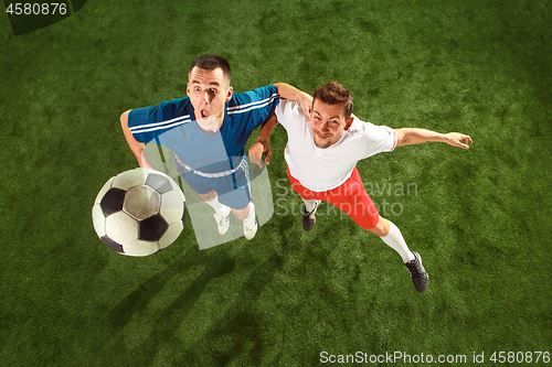 Image of Football players tackling for the ball over green grass background