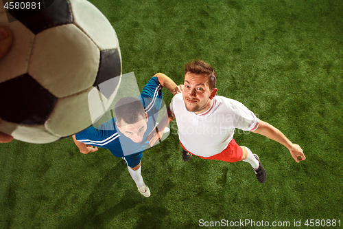 Image of Football players tackling for the ball over green grass background