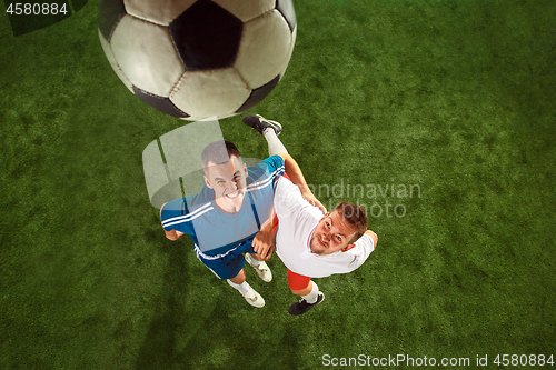 Image of Football players tackling for the ball over green grass background