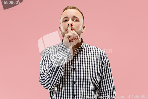 Image of The young man whispering a secret behind her hand over pink background