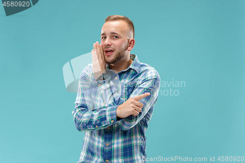 Image of The young man whispering a secret behind her hand over blue background