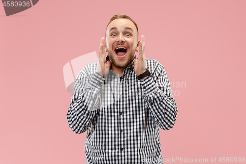 Image of The young attractive man looking suprised isolated on pink