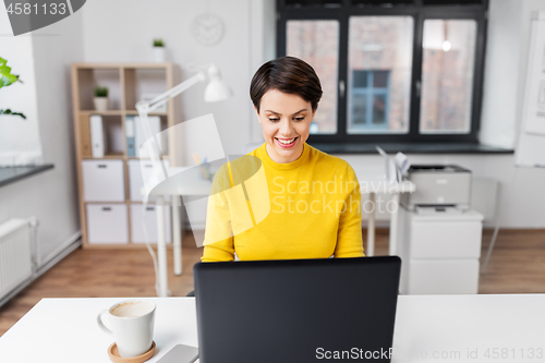 Image of happy businesswoman with laptop working at office