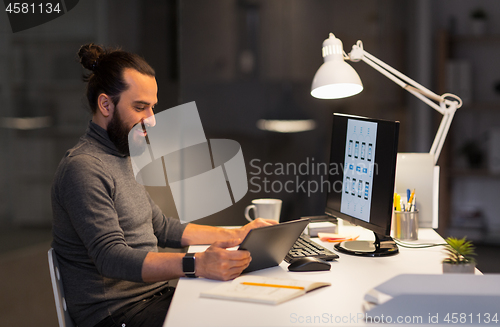 Image of creative man with computer working at night office