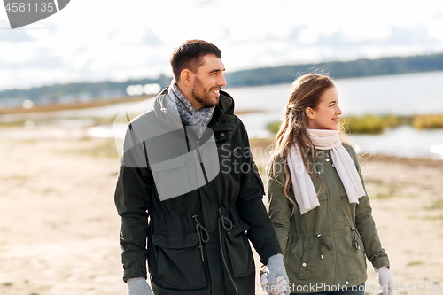 Image of happy couple at autumn beach holding hands