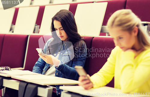 Image of student girls with smartphones on lecture