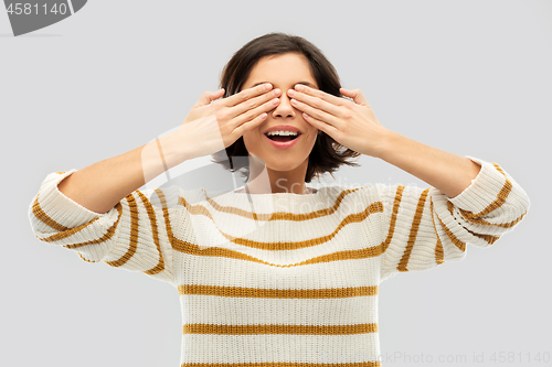 Image of happy smiling woman closing her eyes by hands