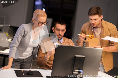 Image of business team with computer working late at office