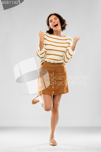 Image of young woman in striped pullover, skirt and shoes