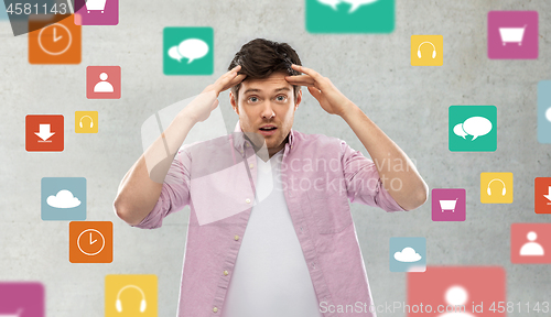 Image of man touching his head over app icons on grey
