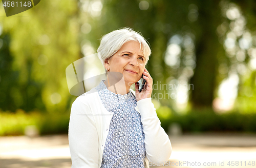 Image of senior woman calling on smartphone in summer park