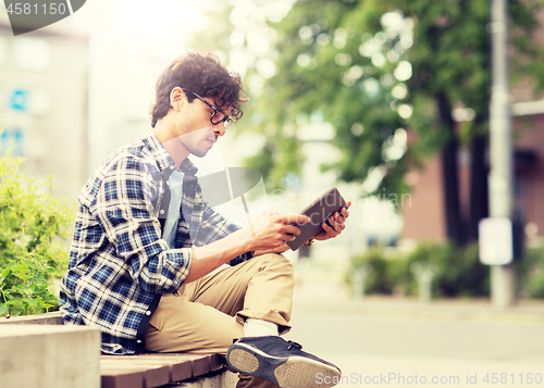 Image of man with tablet pc sitting on city street bench