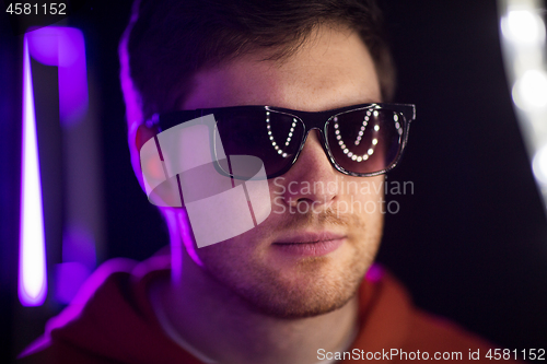 Image of man in sunglasses over ultra violet neon lights