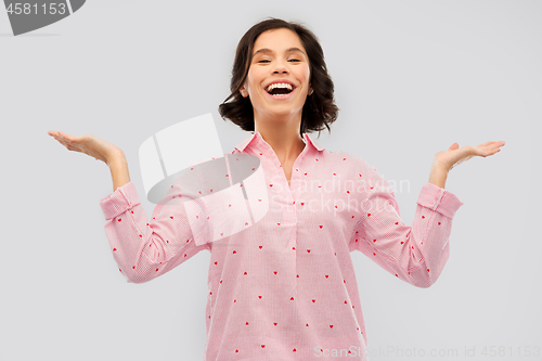 Image of happy young woman in pajama shrugging