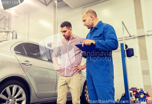 Image of auto mechanic with clipboard and man at car shop