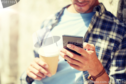 Image of man with smartphone and coffee on city street