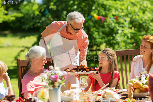 Image of family having dinner or barbecue at summer garden