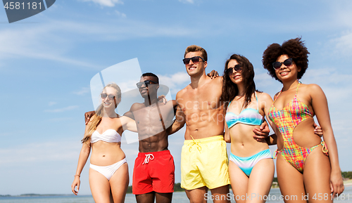 Image of happy friends hugging on summer beach