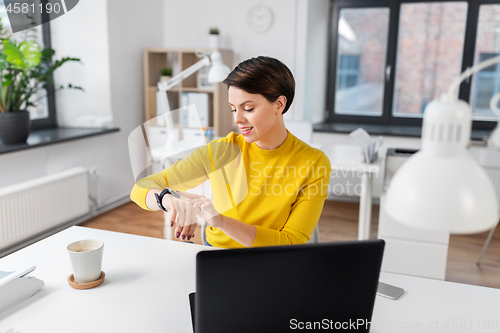 Image of happy businesswoman using smart watch at office