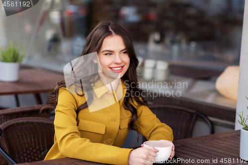 Image of teenage girl drinking hot chocolate at city cafe