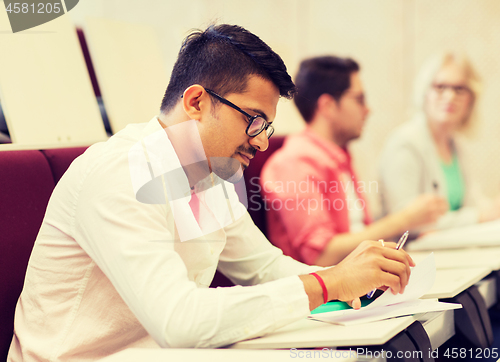 Image of group of students with notebooks in lecture hall