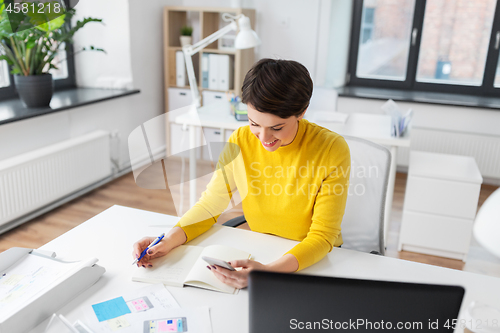 Image of smiling ui designer using smartphone at office