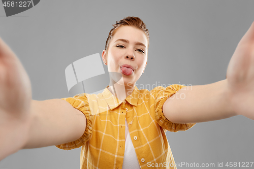 Image of red haired teenage girl taking selfie with tongue