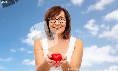 Image of portrait of smiling senior woman holding red heart